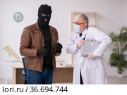 Masked man burglar bribing old doctor for getting vaccine. Стоковое фото, фотограф Elnur / Фотобанк Лори