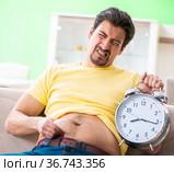 Man suffering from extra kilos in time management concept. Стоковое фото, фотограф Elnur / Фотобанк Лори