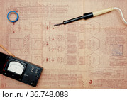 Аналоговый омметр, электрический паяльник, изоляционная лента лежат на старом чертеже с электрическими схемами (2021 год). Редакционное фото, фотограф Цибаев Алексей / Фотобанк Лори