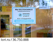 Информационный плакат с надписью "Все сотрудники вакцинированы" на входной двери продовольственного супермаркета. Эпидемия коронавируса COVID-19 в России. Калининград (2021 год). Редакционное фото, фотограф Ирина Борсученко / Фотобанк Лори