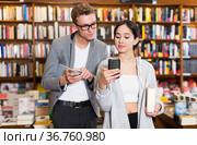 Glad people holding mobile phone at bookshop. Стоковое фото, фотограф Яков Филимонов / Фотобанк Лори