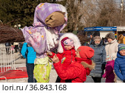 Мама с дитём на руках стоят возле чучела Масленицы на празднике Проводы зимы, среди толпы людей, весной. Красноярск. Россия. (2021 год). Редакционное фото, фотограф Светлана Попова / Фотобанк Лори