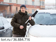 Portrait of Caucasian adult man with snow brush in hands, standing close to his snowy car in winter season. Стоковое фото, фотограф Кекяляйнен Андрей / Фотобанк Лори