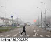 Москва, улица Академика Королева, СВАО. Мужчина переходит улицу по пешеходному переходу. Город окутан  плотным туманом (2021 год). Редакционное фото, фотограф Наталья Николаева / Фотобанк Лори