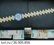 Черный офисный портфель, рублевые купюры торчат из под крышки. Оградительная лента с эмблемой налоговой инспекции и надписью "налоги" (2021 год). Редакционное фото, фотограф Цибаев Алексей / Фотобанк Лори