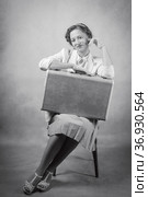 Young woman, dressed in retro style, sitting on a chair, with a suitcase on her knees. Studio black and white shot. Стоковое фото, фотограф Вадим Орлов / Фотобанк Лори