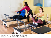 Woman pulling stretch band sitting on pilates training machin. Стоковое фото, фотограф Яков Филимонов / Фотобанк Лори