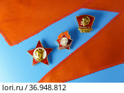 Советские значки для октябрят, пионеров и комсомольцев СССР и красный пионерский галстук на голубом фоне (2021 год). Редакционное фото, фотограф Sergei Gorin / Фотобанк Лори