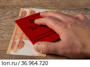 Мужская рука на пенсионном удостоверении РФ и наличных деньгах - паре пятитысячных рублевых купюр. Стоковое фото, фотограф Sergei Gorin / Фотобанк Лори