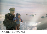 Портрет молодого военного вместе с малышом, он улыбается поддерживая ребенка, они стоят на прибрежном айсберге и любуются морским пейзажем, Чукотка, 1970. Редакционное фото, фотограф Варфоломей Тетерин / Фотобанк Лори