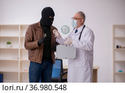 Masked man burglar bribing old doctor for getting vaccine. Стоковое фото, фотограф Elnur / Фотобанк Лори