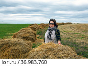 Женщина на фоне стогов сена, уходящих за горизонт. Деревня Моховое. Куркинский район. Тульская область (2021 год). Стоковое фото, фотограф Сергей Афанасьев / Фотобанк Лори