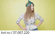 Housewife in shirt and bandage on her head on yellow background. Woman in cleaning clothes puts her hands on her hips. Pensive face. Perplexed person. Woman is thinking about cleaning Tidying up house. Стоковое видео, видеограф Ирина Ткачук / Фотобанк Лори