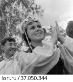 Портрет красивой девушки хлопающий в ладоши, молодая женщина участница творческого коллектива в сценической одежды для выступлений стоит на улице, Якутия, 1965. Редакционное фото, фотограф Варфоломей Тетерин / Фотобанк Лори