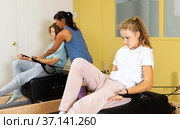 Teen girl pulling stretch band sitting on pilates training machin. Стоковое фото, фотограф Яков Филимонов / Фотобанк Лори