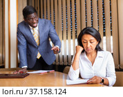 Saddened businesswoman sitting in office with dissatisfied male colleague. Стоковое фото, фотограф Яков Филимонов / Фотобанк Лори