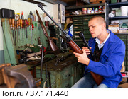 Gunsmith attaches a telescopic sight to rifle in weapons workshop. Стоковое фото, фотограф Яков Филимонов / Фотобанк Лори
