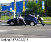 Молодые люди толкают заглохший на дороге автомобиль. Уссурийская улица. Район Гольяново. Город Москва (2013 год). Редакционное фото, фотограф lana1501 / Фотобанк Лори