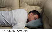Tired exhausted millennial man falling down on sofa at home after hard working day, burnout concept. Стоковое видео, видеограф Данила Большаков / Фотобанк Лори