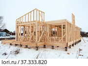 Wood frame house under construction, bare frame with pile foundation, winter season. Стоковое фото, фотограф Кекяляйнен Андрей / Фотобанк Лори