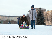 Caucasian family with winter tubing toboggan, father push her child from slope. Стоковое фото, фотограф Кекяляйнен Андрей / Фотобанк Лори