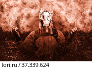 A shot of a man dressed in a gas mask, a hooded jacket, a backpack, praying, with his hands tinged slightly forward and to the sides. A poster on the background of grunge. Стоковое фото, фотограф Владимир Арсентьев / Фотобанк Лори