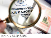 Бухгалтер изучает под увеличительным стеклом выпущенный приказ Федеральной налоговой службой Российской Федерации (2020 год). Редакционное фото, фотограф Николай Винокуров / Фотобанк Лори