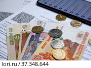 Оплата услуг ЖКХ. Деньги смартфон и квитанции за отопление на столе. Коммунальные платежи. Стоковое фото, фотограф Гребенев Пётр / Фотобанк Лори
