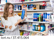 Young woman choosing hair fixation spray in cosmetics store. Стоковое фото, фотограф Яков Филимонов / Фотобанк Лори