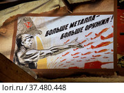 Советский плакат с надписью "Больше металла - больше оружия!" висит на стене в городе Москве, Россия (2022 год). Редакционное фото, фотограф Николай Винокуров / Фотобанк Лори