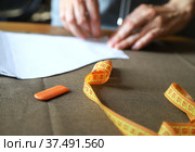 Рабочее место портного. Женщина прикалывает выкройку к ткани. Working process of a dressmaker. Closeup photo with selective focus. Стоковое фото, фотограф Ekaterina M / Фотобанк Лори