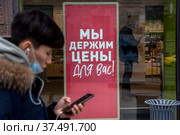 Баннер с надписью "Мы держим цены для вас!" в витрине магазина Yves Rocher на Тверской улице в центре города Москвы, Россия (2022 год). Редакционное фото, фотограф Николай Винокуров / Фотобанк Лори