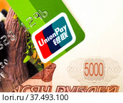 Карта UnionPay на фоне пятитысячной купюры (2022 год). Редакционное фото, фотограф SevenOne / Фотобанк Лори