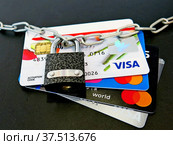 На картах VISA и Mastercard висит замок, черный фон (2022 год). Редакционное фото, фотограф Ludmila Zyubina / Фотобанк Лори