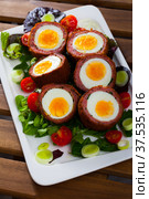 Scotch eggs served with greens and leek, Scottish traditional dish at plate. Стоковое фото, фотограф Яков Филимонов / Фотобанк Лори