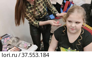 Стилист делает модную красивую прическу ребенку. The stylist makes a fashionable beautiful hairstyle for the child. Редакционное видео, видеограф Мария / Фотобанк Лори