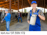 Smiling farmer standing in cowshed at dairy farm with milk churn. Стоковое фото, фотограф Яков Филимонов / Фотобанк Лори