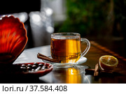 Чашка горячего свежезаваренного чая с лимоном, корицей и шоколадными конфетами в лучах солнца на деревянном темном фоне. Стоковое фото, фотограф Владимир Ходатаев / Фотобанк Лори