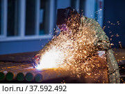 Welder worker in protective mask. Welding steel tubes on manufacturing plant. Sparks and smoke. On blue abstract factory background. Стоковое фото, фотограф Alexey Rezvykh / Фотобанк Лори