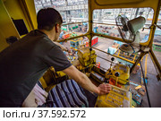 Stepnogorsk, Kazakhstan April 04, 2012: Bearing production plant. Overhead crane operator in cabin. Factory workshop on background. Man is out-of focus. Control levers in focus. Редакционное фото, фотограф Alexey Rezvykh / Фотобанк Лори