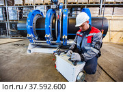 Stepnogorsk, Kazakhstan - April 04, 2012: Plastic pipes production plant. Engineer adjusting pipes joining equipment. Редакционное фото, фотограф Alexey Rezvykh / Фотобанк Лори