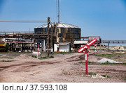 Old rusted oil storage tank and broken railway sign on old soviet factory (plant) against blue sky background. Стоковое фото, фотограф Alexey Rezvykh / Фотобанк Лори