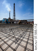 Modernization of outdated phosphate fertilizer plant. Industrial building construction. Workers assembling steel reinforcement of basement. Industrial building and blue sky on background. Стоковое фото, фотограф Alexey Rezvykh / Фотобанк Лори