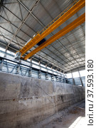 Grey concrete interior of new industrial building. New factory workshop of phosphoric fertilizers plant. Yellow overhead crane. Стоковое фото, фотограф Alexey Rezvykh / Фотобанк Лори
