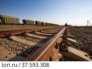 Phosphate fertilizers plant. Railway loader station of fertilizers. Green hopper railway carriages train on horizon. Close-up of rails on foreground. Clear blue sky background. Panorama view. Стоковое фото, фотограф Alexey Rezvykh / Фотобанк Лори