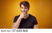 Thoughtful young man pondering something, touching his chin, yellow background. Стоковое видео, видеограф Сергей Толмачёв / Фотобанк Лори