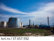 Grey oil storage tanks on bright sun on blue sky with light clouds. Oil refinery plant in desert. Near Taraz city, Kazakhstan. Стоковое фото, фотограф Alexey Rezvykh / Фотобанк Лори