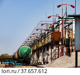 Railway oil tank filling terminal on oil refinery plant in desert. Anti-fire system with extinguishers. Blue sky background. Taraz city. (2012 год). Редакционное фото, фотограф Alexey Rezvykh / Фотобанк Лори