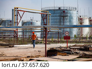 Taraz, Kazakhstan - April 25 2012: Oil refinery and gas processing plant warehouse. Steel storage tanks and orange dump truck with ground. Редакционное фото, фотограф Alexey Rezvykh / Фотобанк Лори