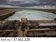 Small Aral Sea Kok-aral dam. Kazakhstan, Kyzylorda region. Concrete supports, metal shutters, turbulent water after dam. Grey storm sky. Стоковое фото, фотограф Alexey Rezvykh / Фотобанк Лори